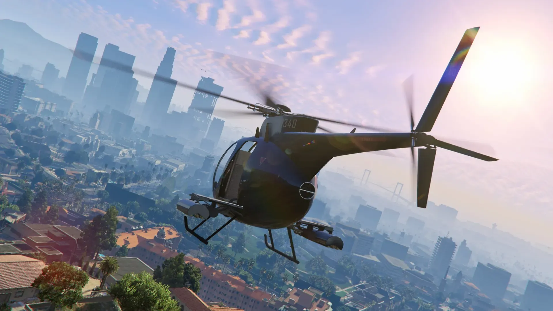 A black Buzzard attack helicopter with weapon pods flies low over Los Santos under a pink sky