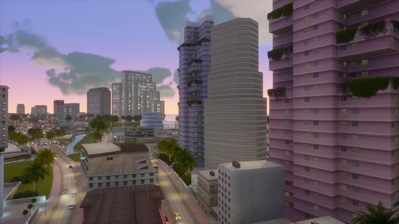 View from high up between apartment towers over a canal, palm lined roads and the city skyline at dusk
