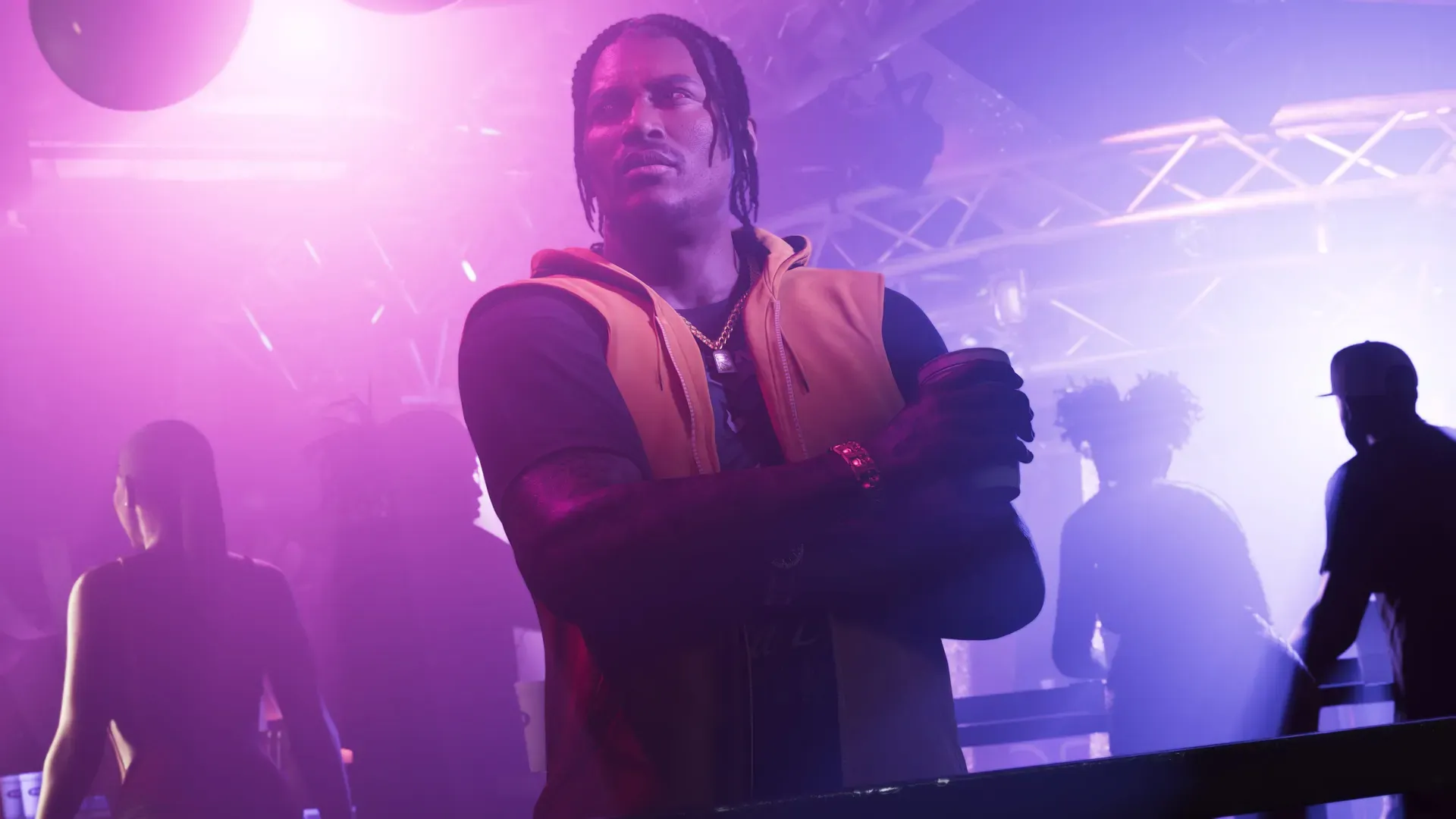 Dre'Quan in a club crossing his arms with a drink in his hand looking off to the side.