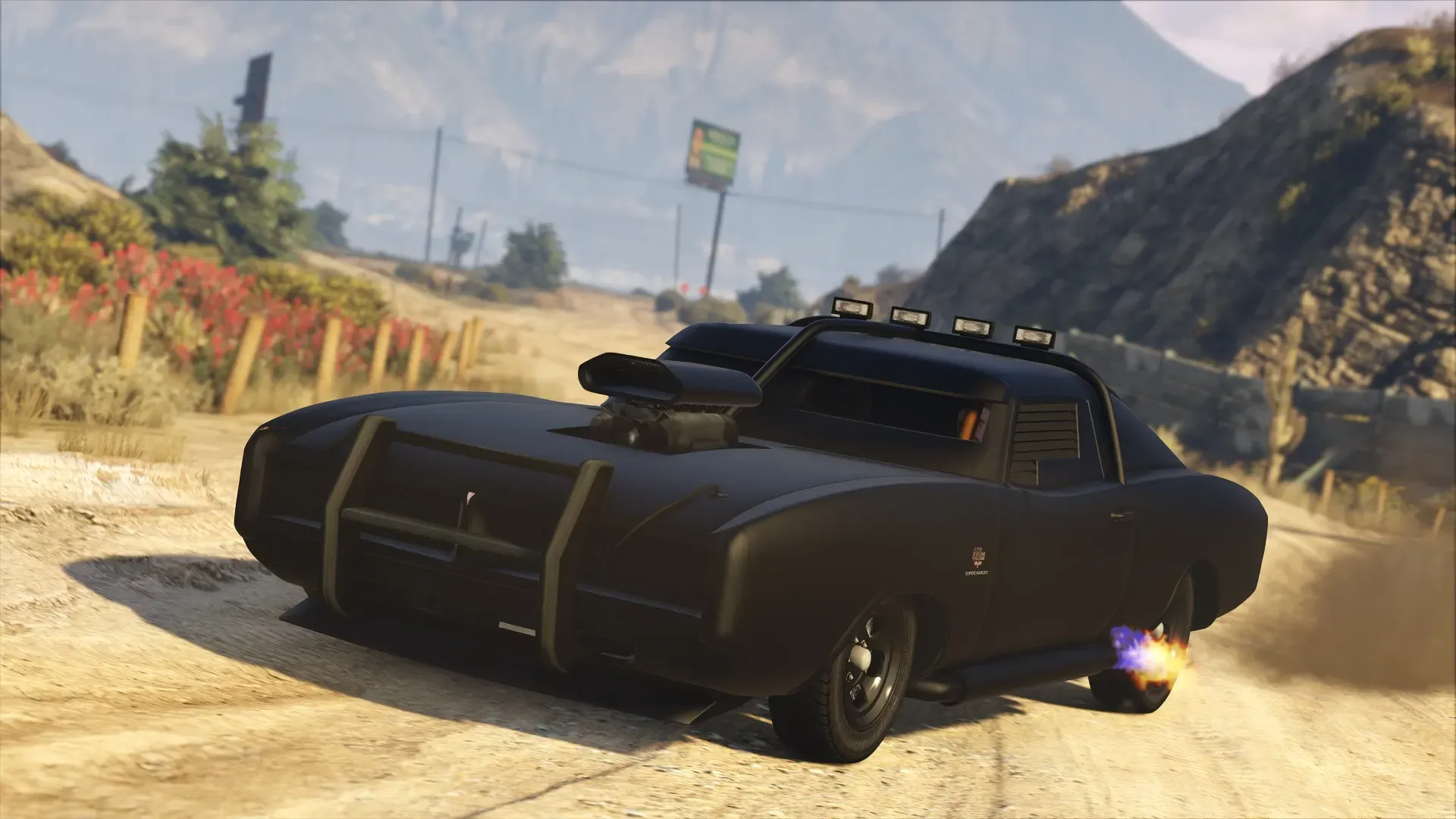 Official Rockstar image of the Imponte Duke O'Death, a matte black armored muscle car, kicking up dust on a desert road