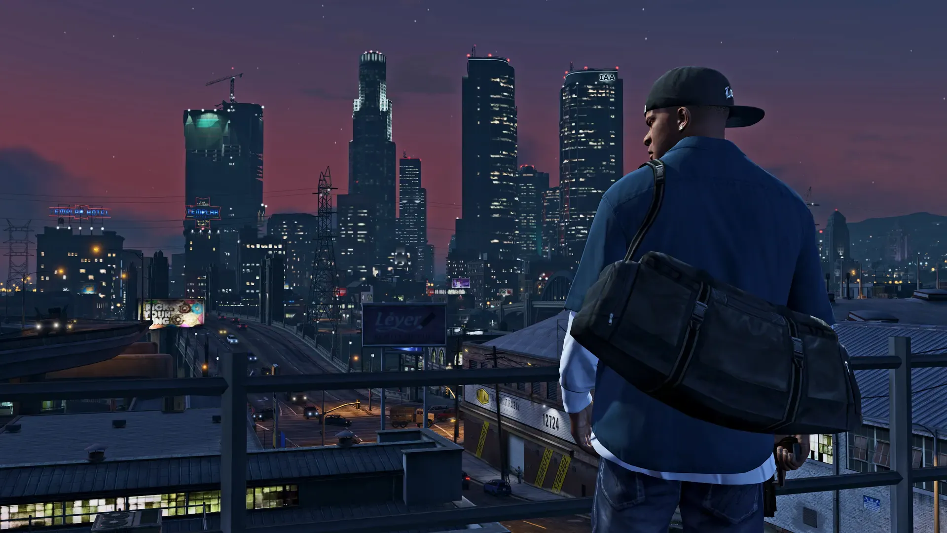 Franklin with a duffel bag on his shoulder looks out over the lit towers of downtown Los Santos at dusk