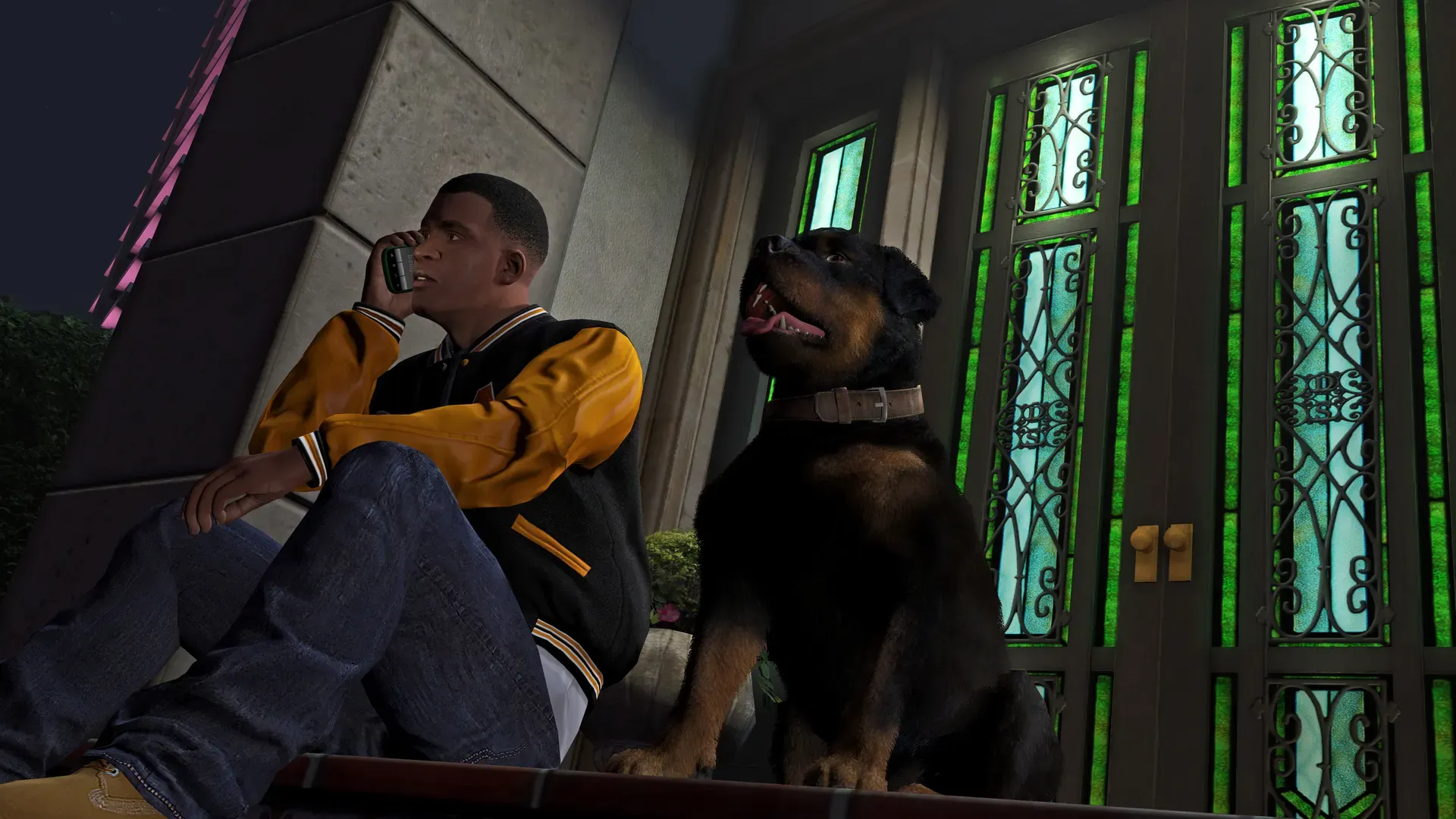 Franklin talks on his phone on a doorstep at night as Chop sits beside him