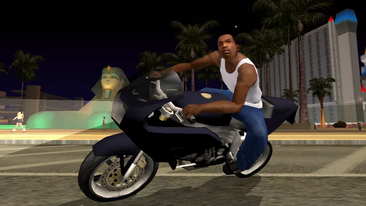 Original game, 2013 mobile release: CJ rides a sports motorcycle at night past a sphinx statue and tall casino buildings