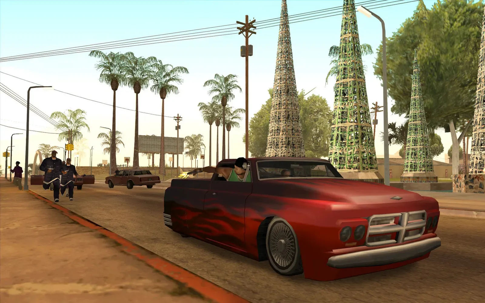 Original game (PC): a red lowrider with flame paint drives past tall lattice towers and palm trees on a sunny street