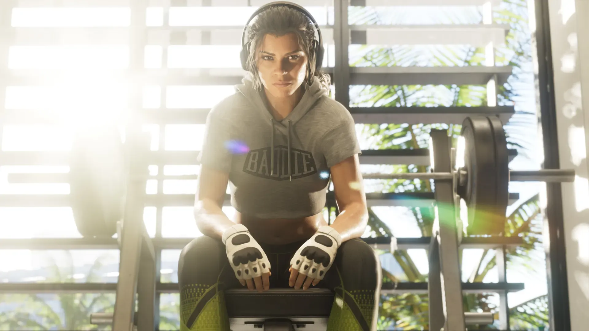 Lucia wearing headphones and gloves, sitting on a weight bench in an outdoor gym.