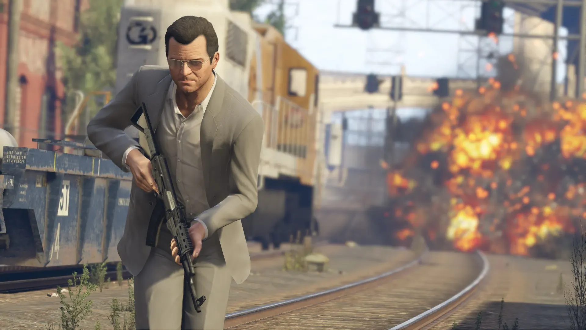 Michael in a suit runs along a rail yard holding a rifle as a train explodes behind him