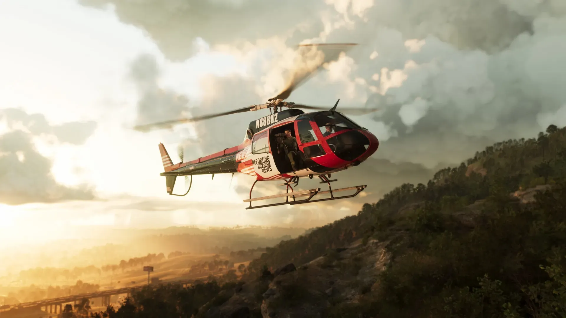 A news helicopter flying over a tree-filled ridge in Mount Kalaga National Park.
