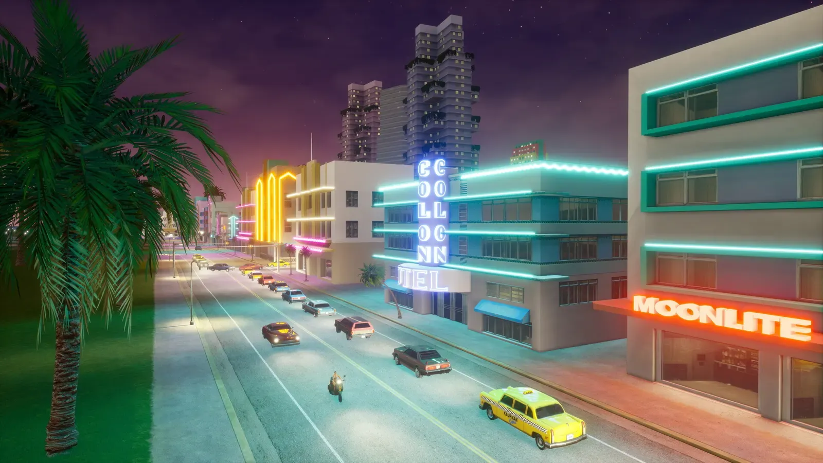 Neon lit Art Deco hotels, including the Colonnade and the Moonlite, line a busy beachfront road at night, seen past a palm tree