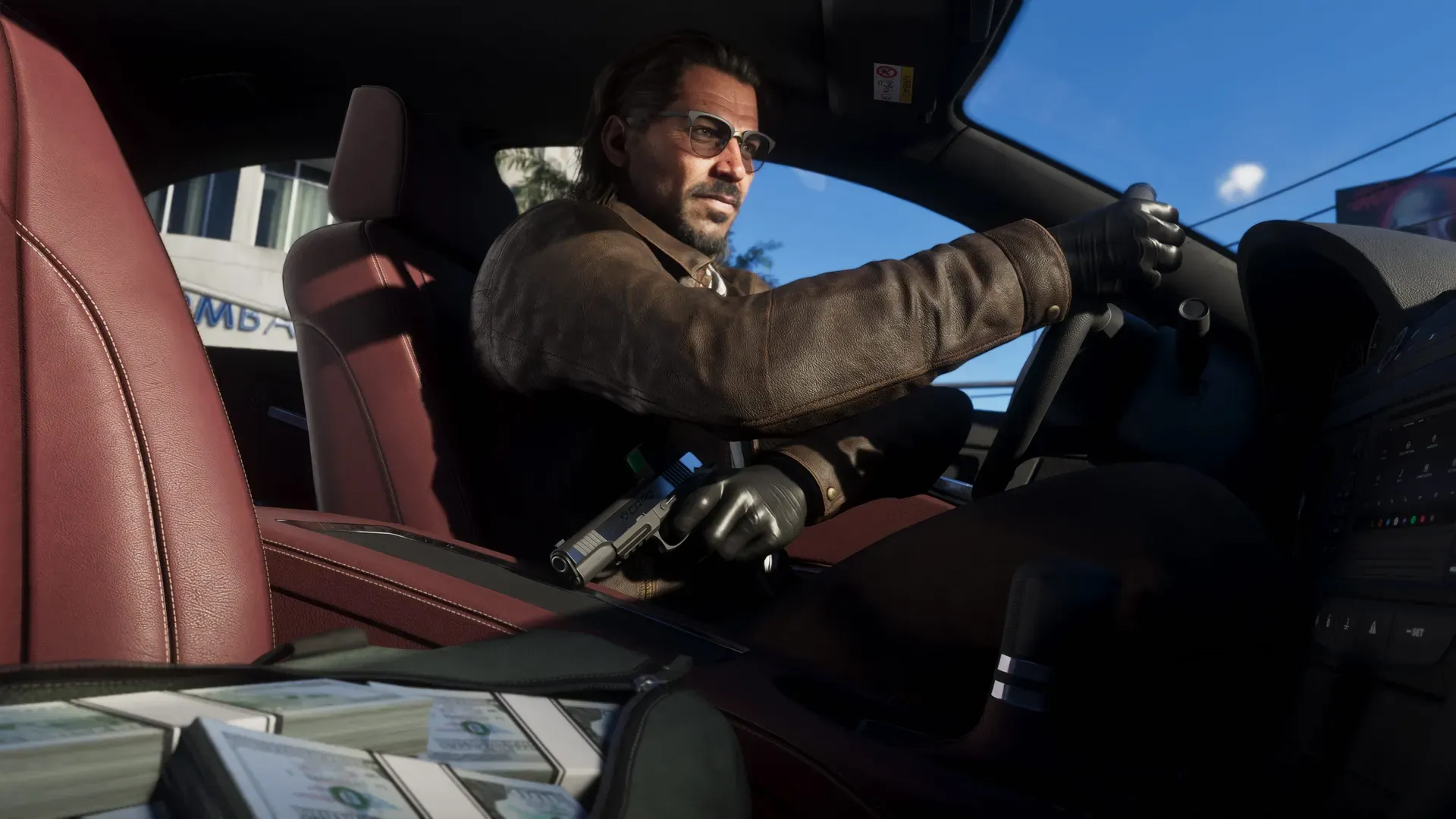 Raul driving with one hand and holding a handgun hidden with the other. A bag full of cash sits open next to him in the passenger seat.