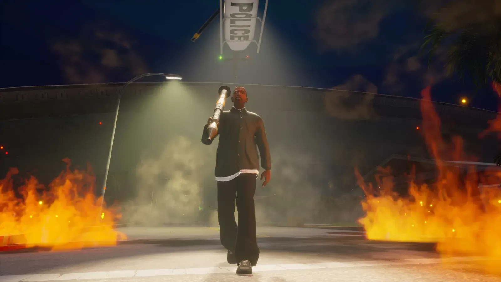 Definitive Edition: a man carries a rocket launcher on his shoulder down a burning street at night as a police helicopter shines its light from above