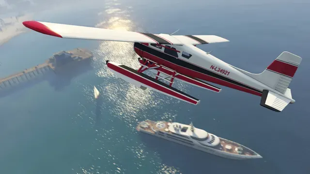 A white and red seaplane banks over the ocean near a pier, with a large yacht below