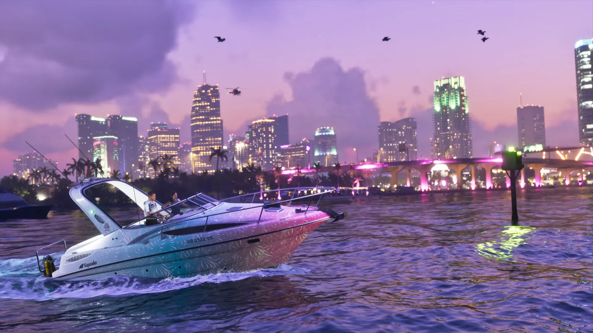 A gradient pink and blue Squalo moves through the water at night, with the illuminated city skyline in the background.