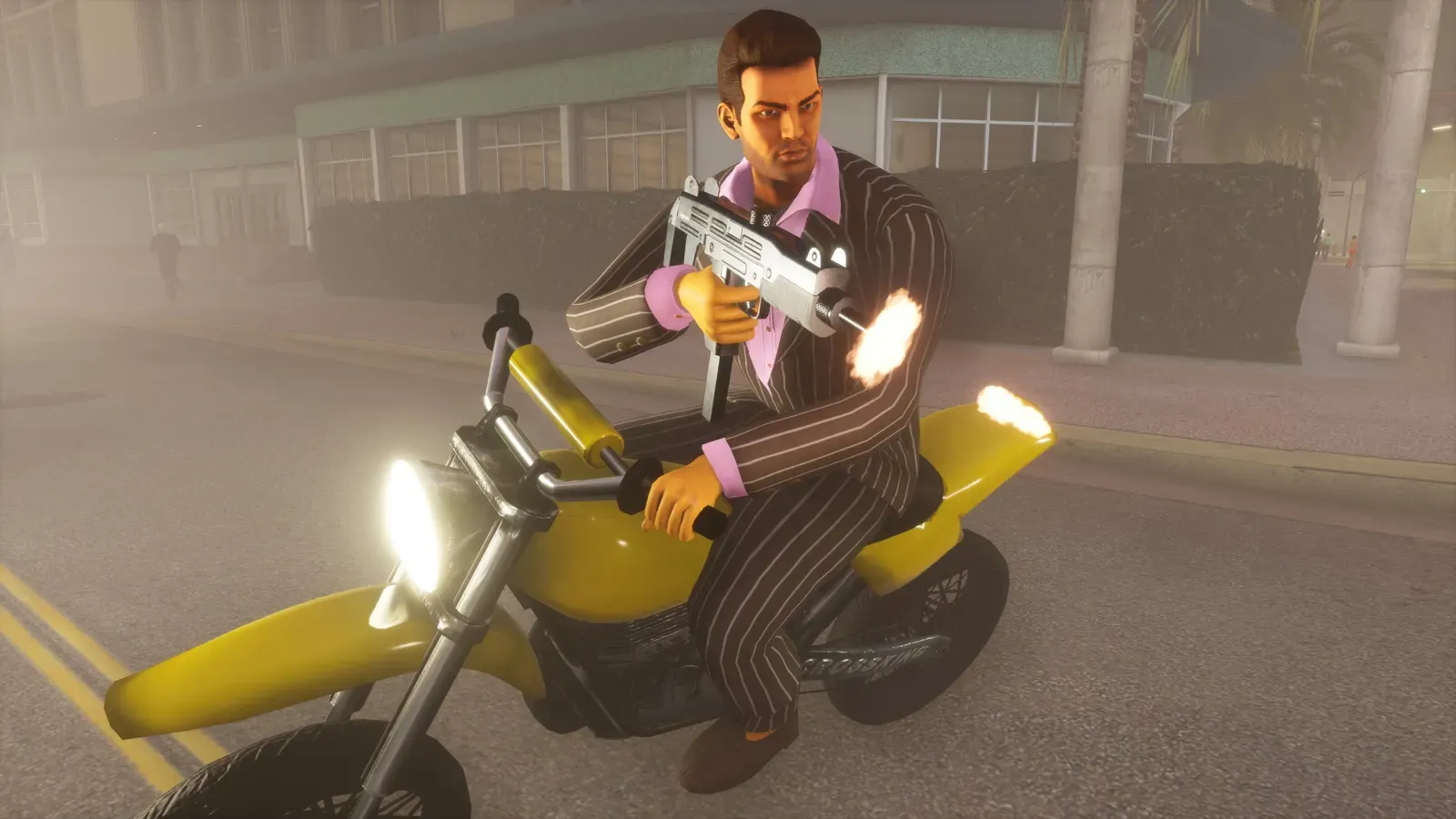 Tommy in a pinstripe suit fires a submachine gun while riding a yellow dirt bike along a hazy street
