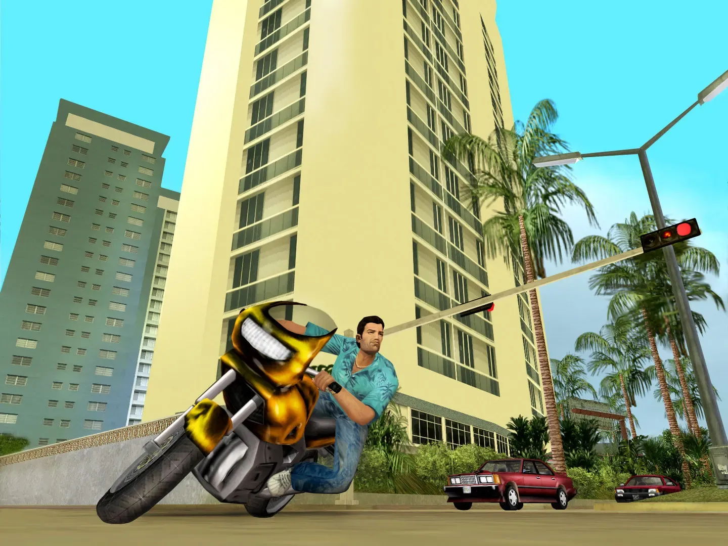 Tommy leans a gold sports motorbike into a turn below tall hotel towers and palm trees