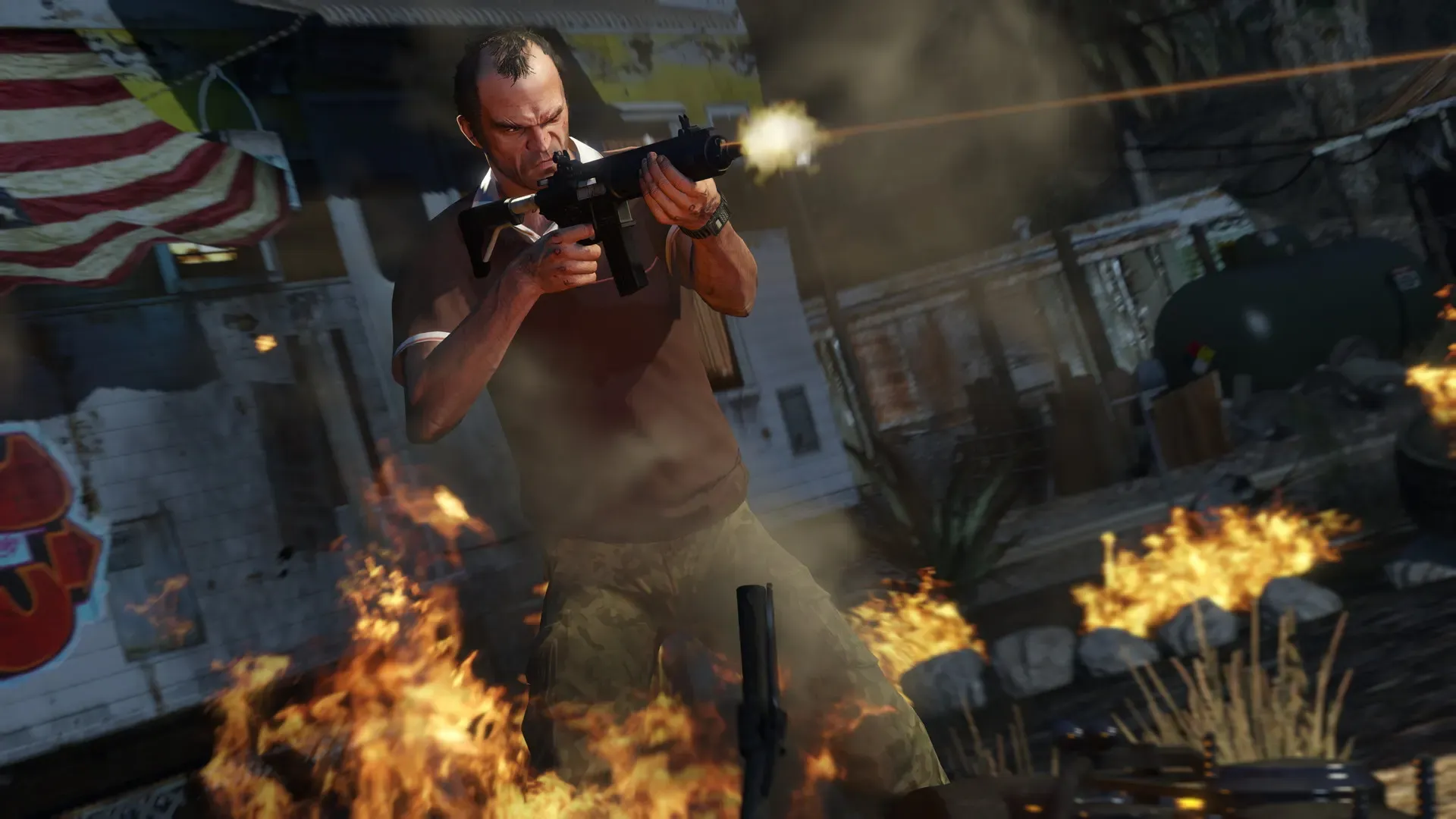 Trevor fires a submachine gun among flames beside a wooden shack
