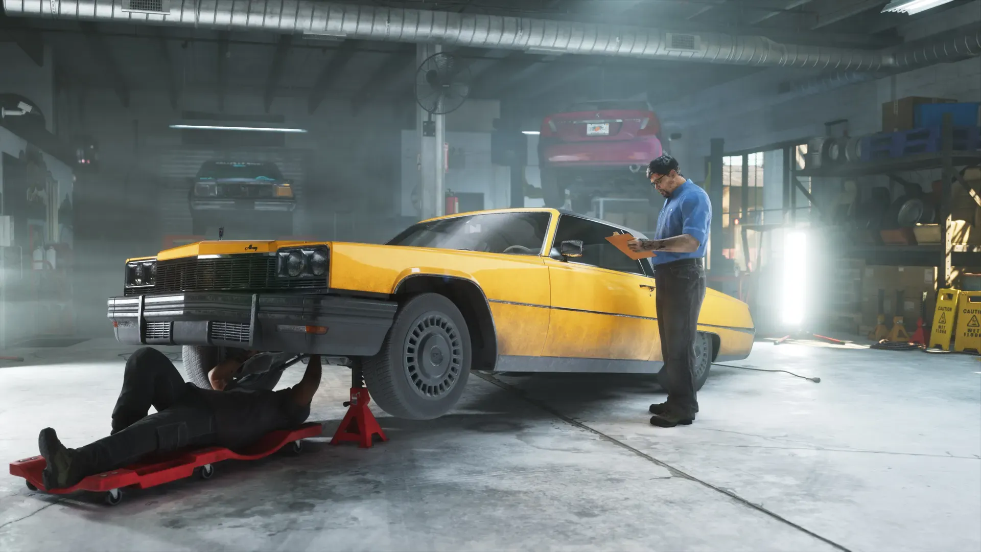 A mechanic inside of Rideout Customs is working underneath a car while another man stands alongside the vehicle.
