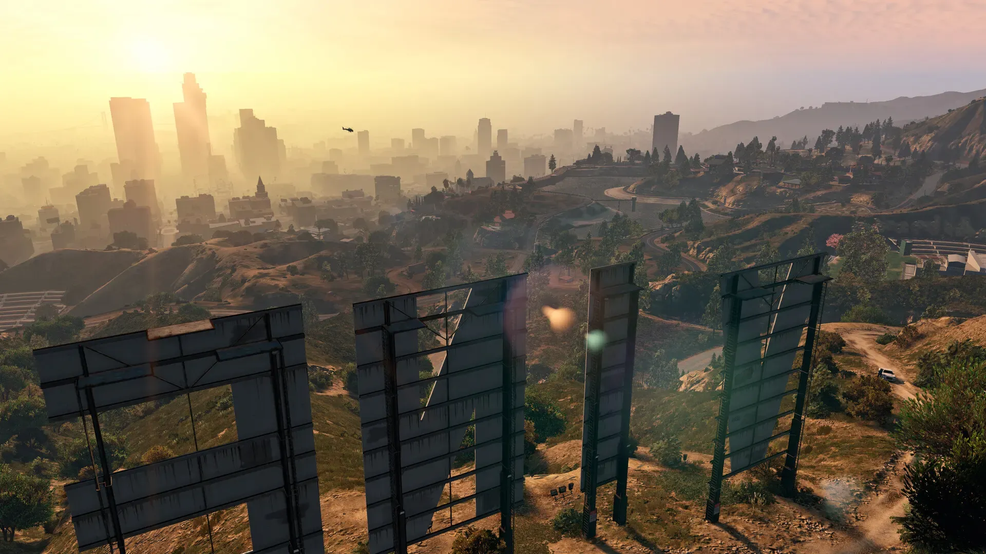 The back of the Vinewood sign on a hillside, looking out over Los Santos in hazy golden light